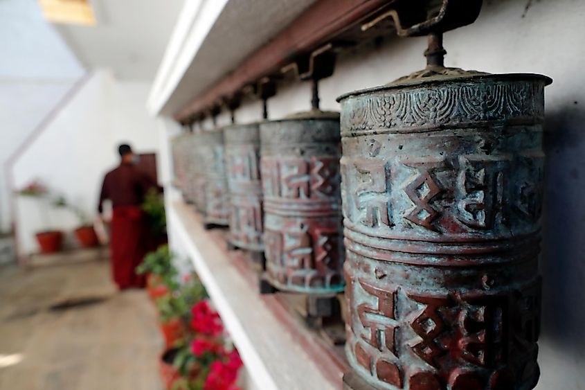 Монастырь Пема Осел Линг.  Крутятся металлические молитвенные барабаны.  Мантра написана на тибетском языке снаружи колеса.