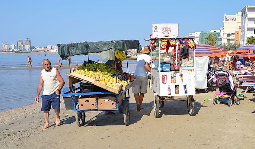 Торговцы едой и фруктами целый день проходят один за другим по пляжу Дурреса, Албания.